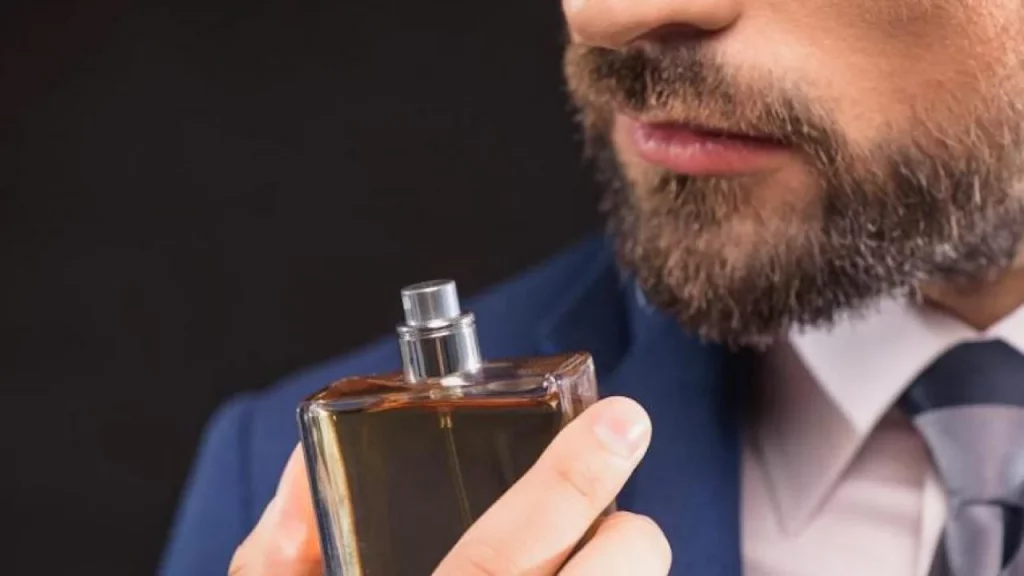 Homem com barba e frasco de perfume